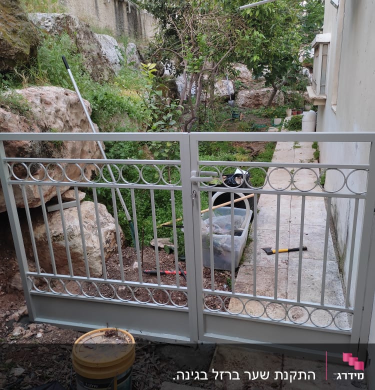 שער מתכת אפור עם עיטורים עגולים בגינה